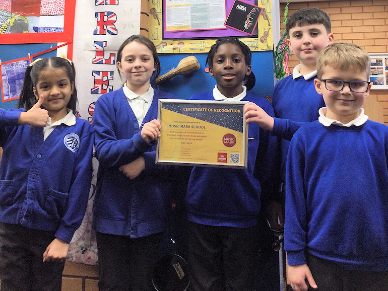 Pupils proudly displaying our Music Mark certificate